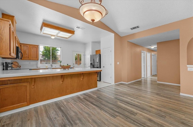 6380 N Cleo, Fresno, CA 93722 - kitchen featuring black appliances, a peninsula, light countertops, light wood finished floors, and brown cabinets
