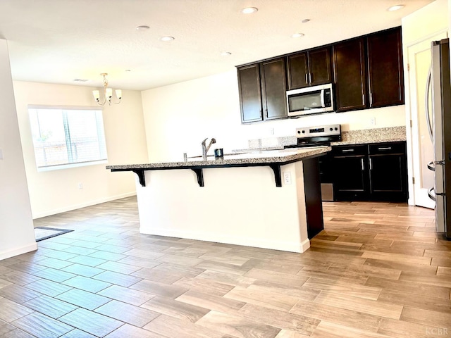 2158 W Ambassador Way, Hanford, CA 93230 - kitchen with stainless steel appliances, a kitchen bar, a chandelier, stone counters, and recessed lighting