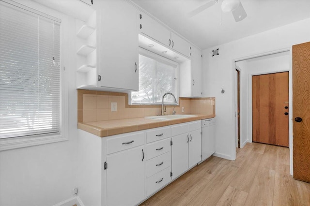 3512 E Simpson Ave, Fresno, CA 93703 - kitchen featuring a sink, tasteful backsplash, white cabinets, light wood-style floors, and baseboards