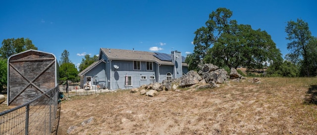 43480 Cave Stone Ct, Coarsegold, CA 93614 - back of house featuring solar panels, a chimney, a patio area, an outbuilding, and fence