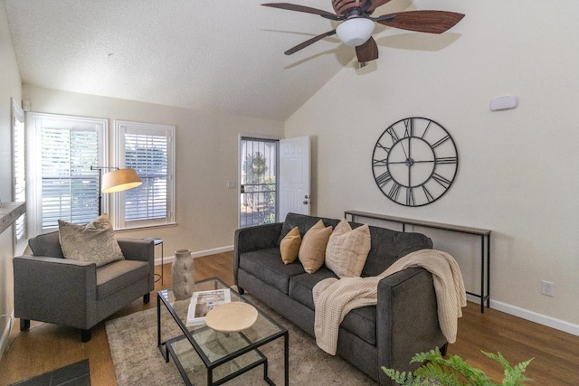 living room with a ceiling fan, vaulted ceiling, baseboards, and wood finished floors