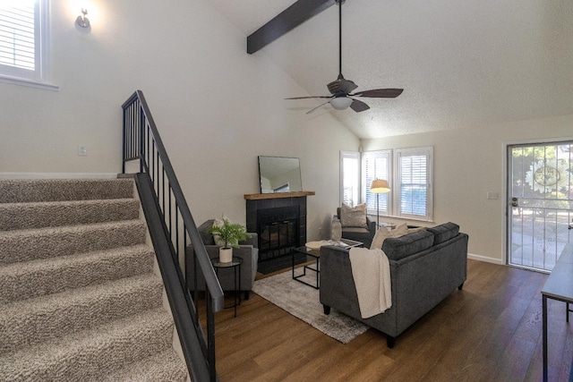 living area with dark wood finished floors, stairway, a fireplace with flush hearth, healthy amount of natural light, and high vaulted ceiling