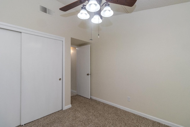 unfurnished bedroom with carpet flooring, a closet, baseboards, and a ceiling fan