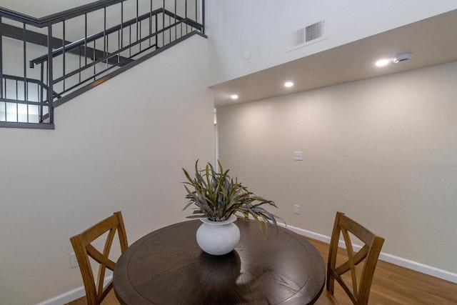 dining room featuring baseboards, wood finished floors, a towering ceiling, stairs, and recessed lighting