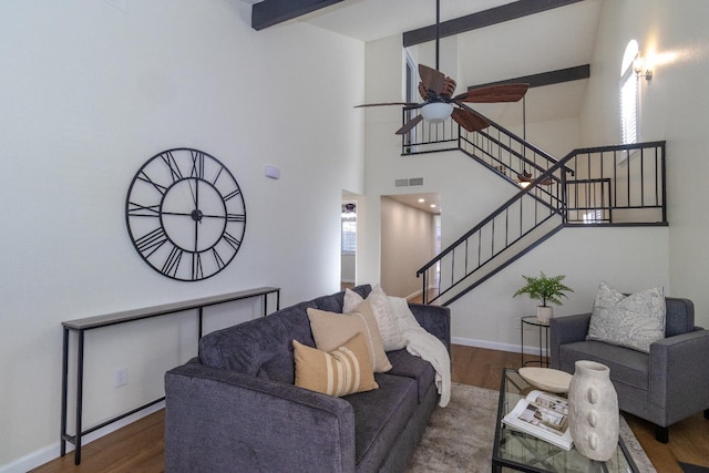 living room with wood finished floors, a ceiling fan, stairs, baseboards, and a high ceiling