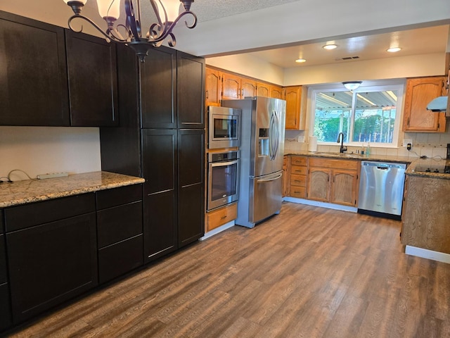 1489 Celeste Ave, Clovis, CA 93611 - kitchen featuring appliances with stainless steel finishes, a sink, dark wood finished floors, light stone counters, and a chandelier