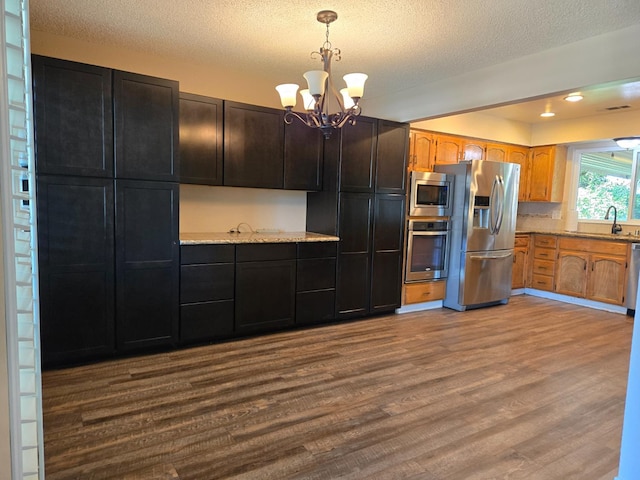1489 Celeste Ave, Clovis, CA 93611 - kitchen with stainless steel appliances, dark wood finished floors, a chandelier, a textured ceiling, and decorative light fixtures