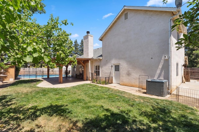 rear view of property with a chimney, central AC unit, a patio, and stucco siding