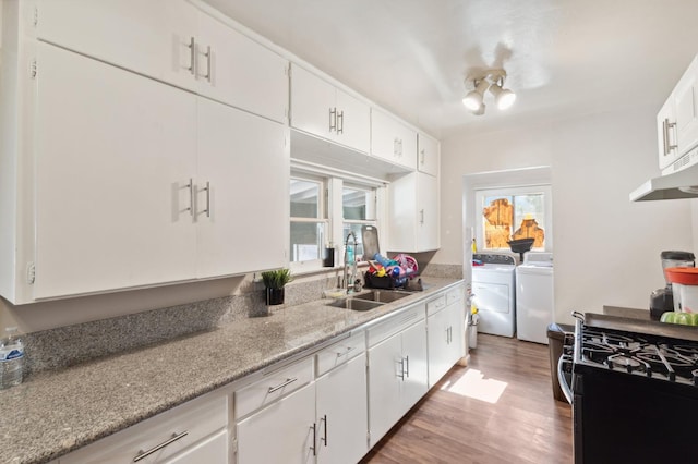 2140 E Floradora Ave, Fresno, CA 93703 - kitchen with washing machine and clothes dryer, gas range, a sink, light wood-style floors, and white cabinetry