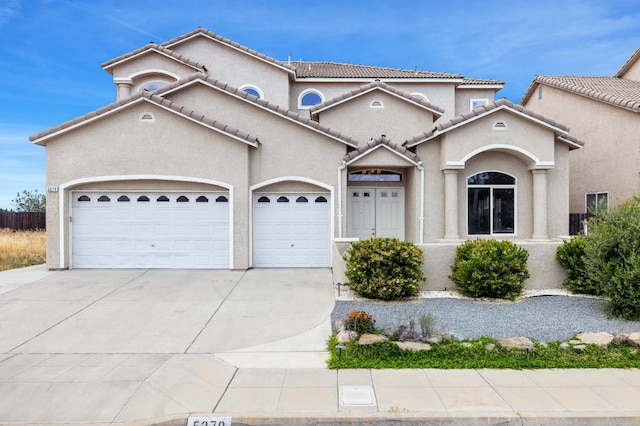 5279 N Ensanada Ave, Fresno, CA 93723 - mediterranean / spanish home featuring an attached garage, driveway, stucco siding, and a tile roof