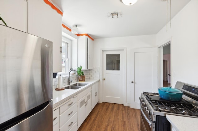 2020 N Fruit Ave, Fresno, CA 93705 - kitchen featuring appliances with stainless steel finishes, a sink, decorative backsplash, wood finished floors, and white cabinetry