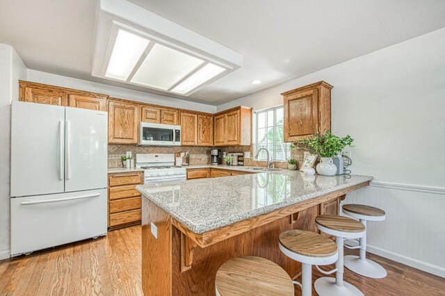 198 Decatur Ave, Clovis, CA 93611 - kitchen with white appliances, a sink, a peninsula, light stone counters, and light wood-style flooring