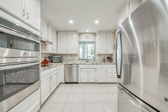 6365 N Barcus Ave, Fresno, CA 93722 - kitchen featuring stainless steel appliances, tasteful backsplash, white cabinets, light tile patterned flooring, and light stone countertops