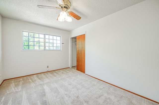 carpeted spare room featuring baseboards, a textured ceiling, and a ceiling fan