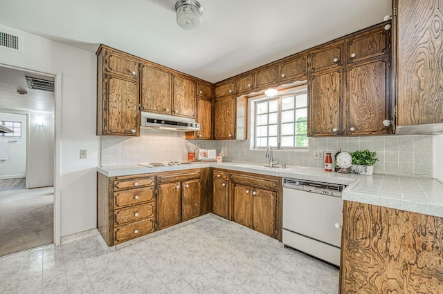 kitchen with white appliances, a sink, under cabinet range hood, and brown cabinetry
