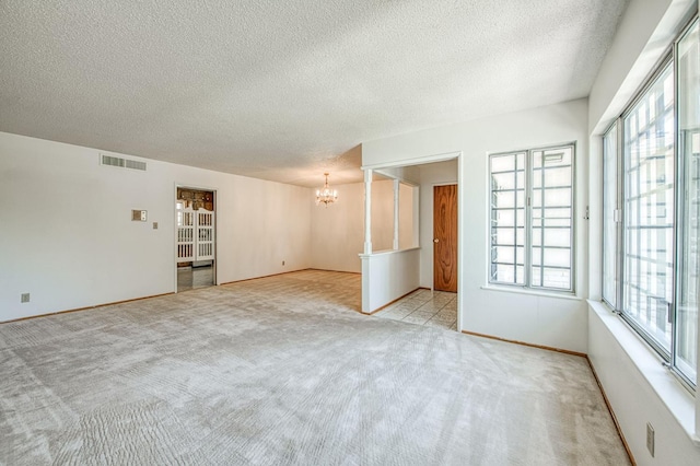 unfurnished room with a chandelier, carpet flooring, a textured ceiling, and baseboards