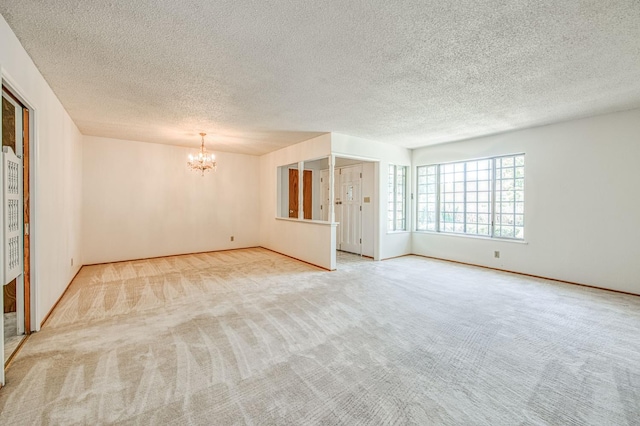 carpeted spare room featuring a chandelier and a textured ceiling