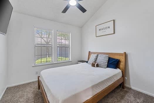bedroom featuring carpet, vaulted ceiling, baseboards, and ceiling fan