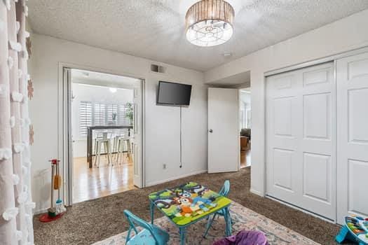 game room with a textured ceiling, carpet floors, and baseboards