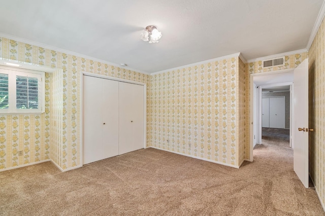 unfurnished bedroom with crown molding, carpet floors, wallpapered walls, and a closet