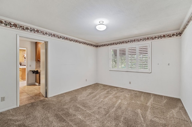 spare room featuring carpet flooring, ornamental molding, and baseboards