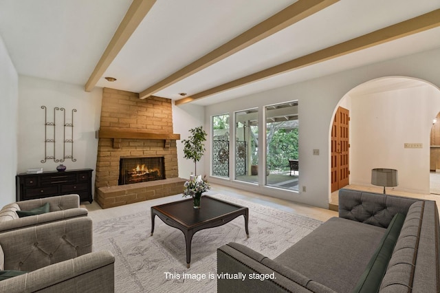 living room with beamed ceiling, arched walkways, a fireplace, and carpet flooring