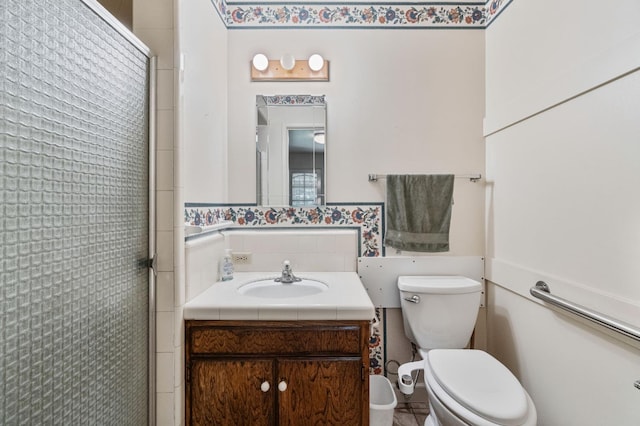 full bathroom featuring a stall shower, toilet, vanity, and tile walls
