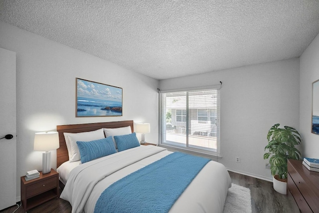 bedroom featuring wood finished floors, a textured ceiling, and baseboards