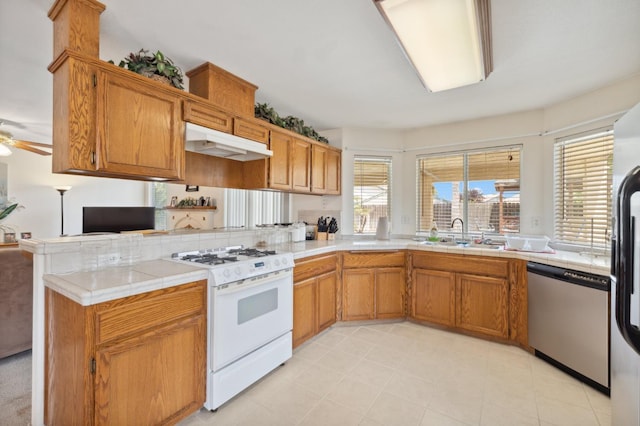 5532 N Cleo Ave, Fresno, CA 93722 - kitchen featuring stainless steel dishwasher, gas range gas stove, under cabinet range hood, a sink, and a peninsula