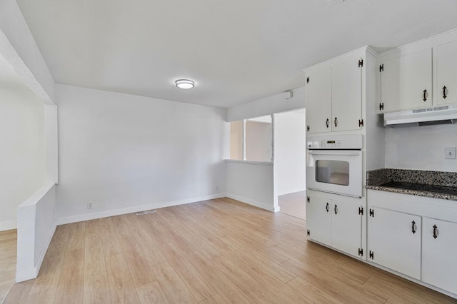 638 W Dennis Dr, Clovis, CA 93612 - kitchen with oven, under cabinet range hood, white cabinetry, light wood-style flooring, and black electric stovetop