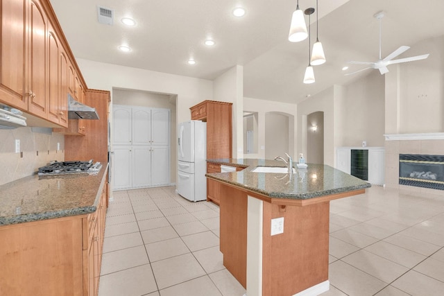 373 W Houston Ave, Clovis, CA 93611 - kitchen with white refrigerator with ice dispenser, under cabinet range hood, a ceiling fan, stainless steel gas cooktop, and arched walkways