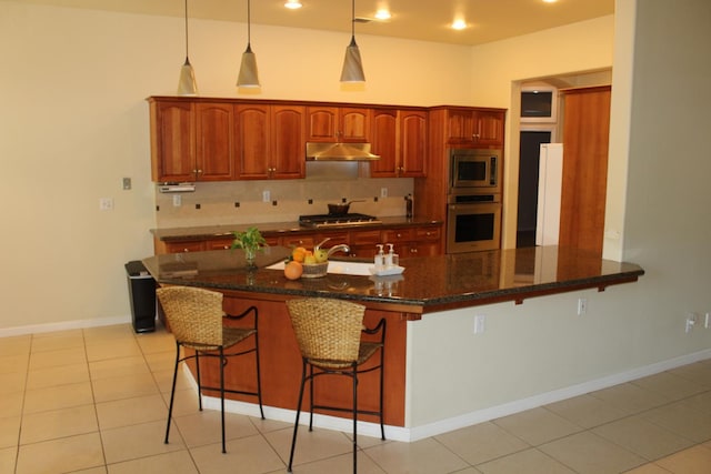 373 W Houston Ave, Clovis, CA 93611 - kitchen featuring appliances with stainless steel finishes, under cabinet range hood, a kitchen breakfast bar, pendant lighting, and dark stone counters