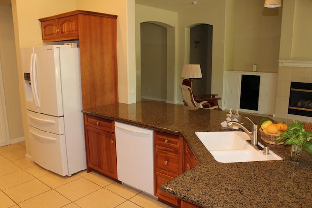 373 W Houston Ave, Clovis, CA 93611 - kitchen featuring white appliances, a sink, light tile patterned floors, a fireplace, and dark stone countertops