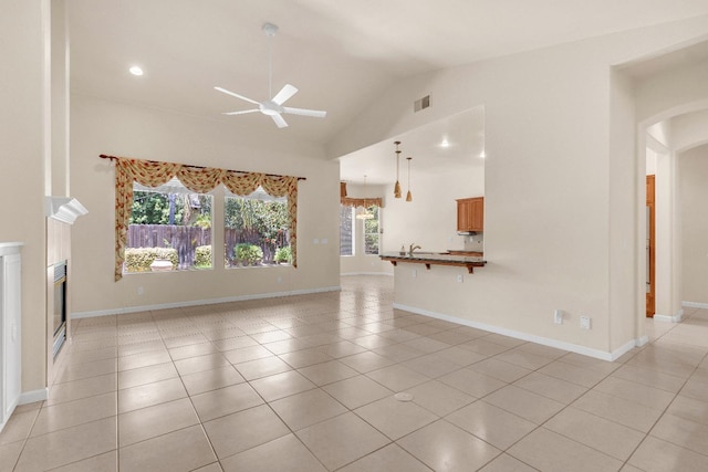 373 W Houston Ave, Clovis, CA 93611 - unfurnished living room with a ceiling fan, vaulted ceiling, arched walkways, light tile patterned flooring, and a glass covered fireplace