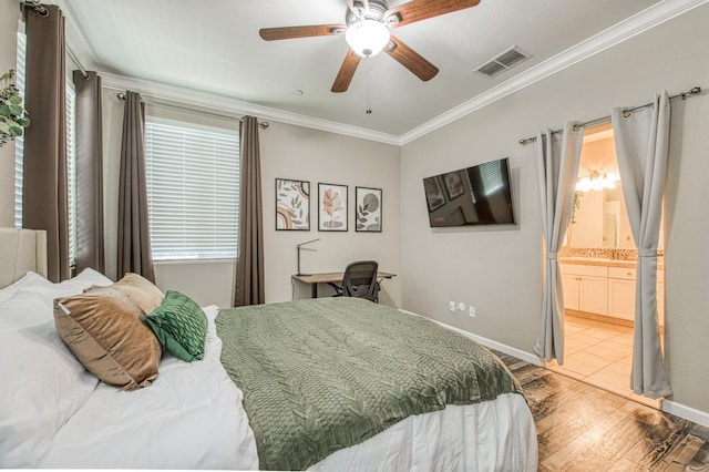 bedroom with light wood finished floors, crown molding, baseboards, a ceiling fan, and ensuite bathroom