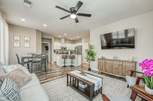 living area featuring wood finished floors, ceiling fan, recessed lighting, and baseboards