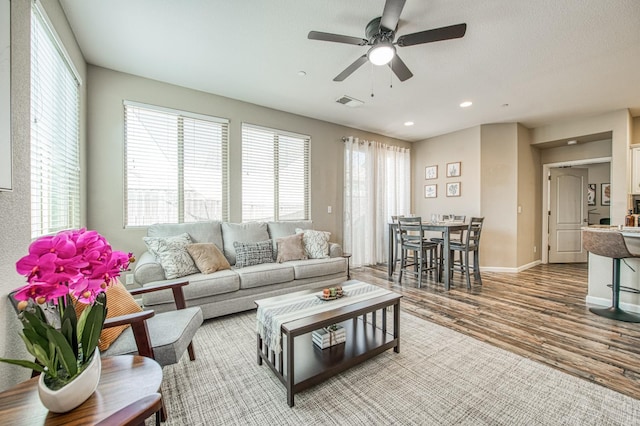 living room with a ceiling fan, wood finished floors, baseboards, and recessed lighting