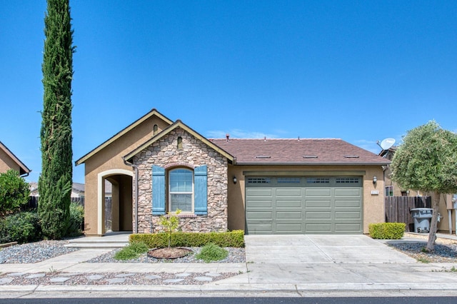 view of front of home featuring stone siding, an attached garage, concrete driveway, stucco siding, and fence