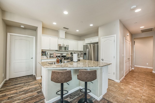 kitchen featuring stainless steel appliances, white cabinetry, a center island with sink, baseboards, and recessed lighting