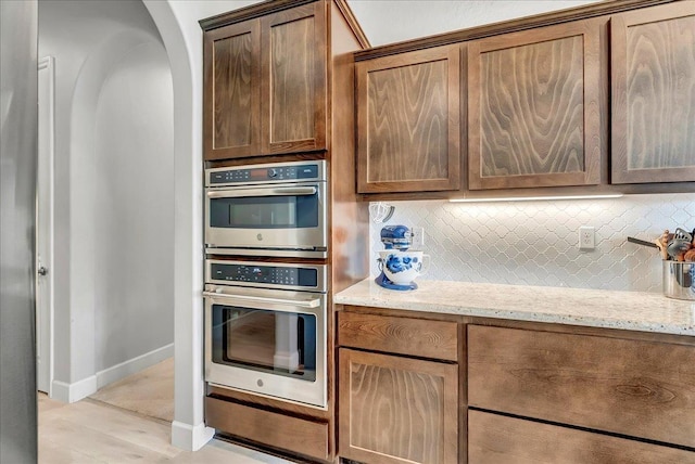 2315 W Malone St, Hanford, CA 93230 - kitchen with double oven, backsplash, light stone counters, baseboards, and light wood-style floors