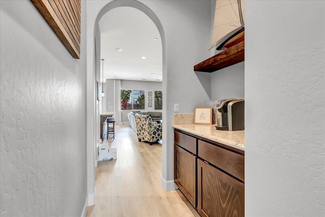 2315 W Malone St, Hanford, CA 93230 - hallway with arched walkways, light wood-style flooring, a textured wall, baseboards, and recessed lighting