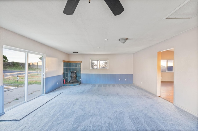 5664 Clouds Rst, Mariposa, CA 95338 - empty room featuring carpet, ceiling fan, a wood stove, and wainscoting