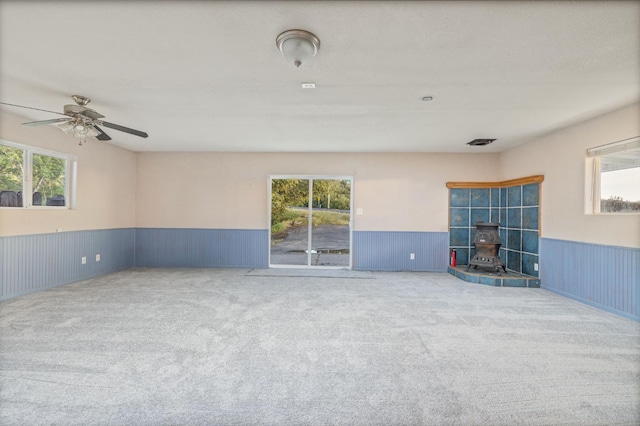 5664 Clouds Rst, Mariposa, CA 95338 - carpeted empty room featuring wainscoting, a wood stove, healthy amount of natural light, and a ceiling fan
