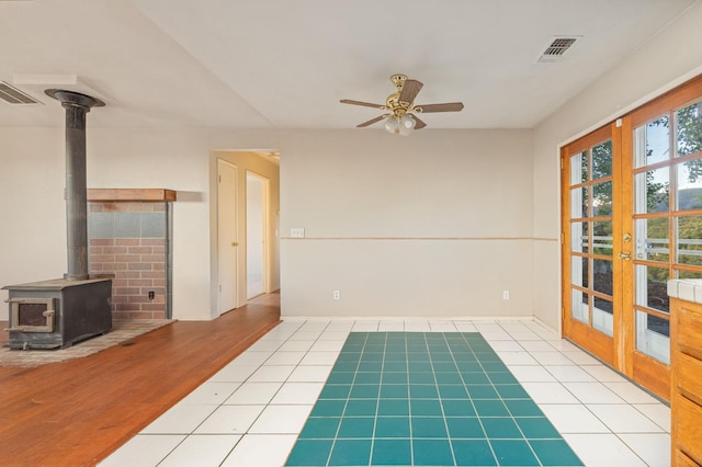 5664 Clouds Rst, Mariposa, CA 95338 - unfurnished living room featuring a wood stove, a ceiling fan, and tile patterned flooring