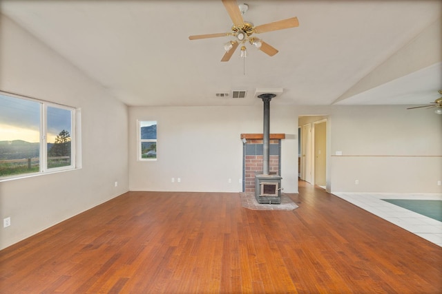 5664 Clouds Rst, Mariposa, CA 95338 - unfurnished living room featuring ceiling fan, a wood stove, wood finished floors, and vaulted ceiling