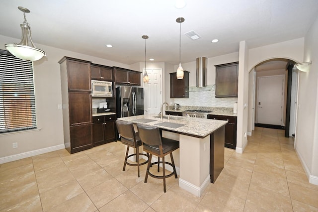 11332 N Cherry Sage Ave, Fresno, CA 93730 - kitchen with stainless steel appliances, wall chimney range hood, decorative backsplash, arched walkways, and recessed lighting