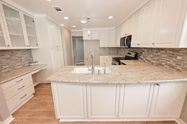 kitchen featuring stainless steel appliances, a sink, a peninsula, light stone counters, and tasteful backsplash