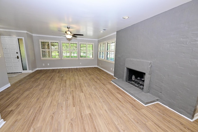 unfurnished living room with a ceiling fan, a fireplace with raised hearth, wood finished floors, crown molding, and baseboards