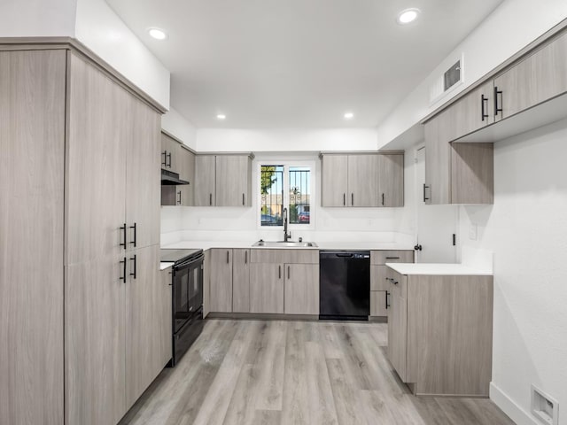 2332 S Jackson Ave, Fresno, CA 93725 - kitchen featuring black appliances, a sink, under cabinet range hood, light brown cabinets, and light wood-style floors