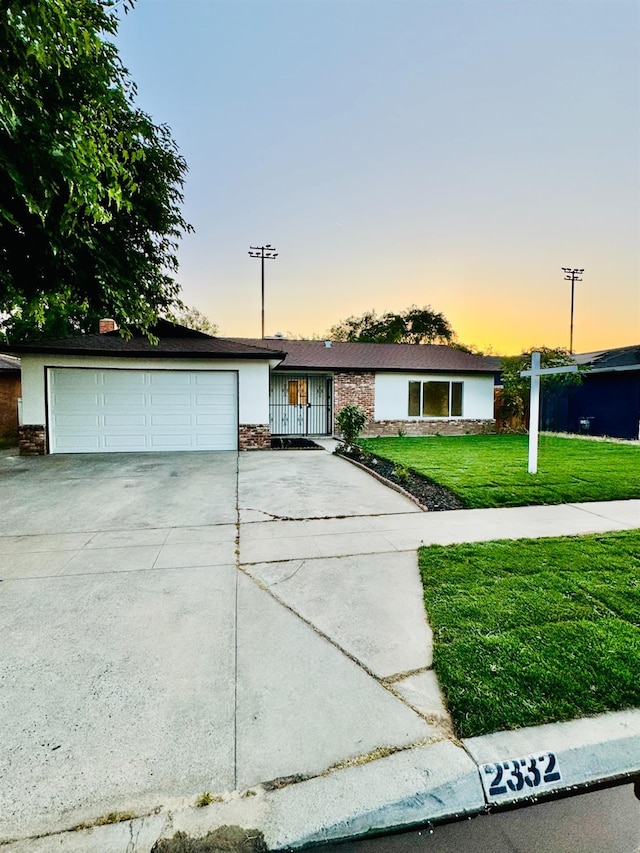 2332 S Jackson Ave, Fresno, CA 93725 - view of front of home with driveway, a garage, a front yard, and stone siding